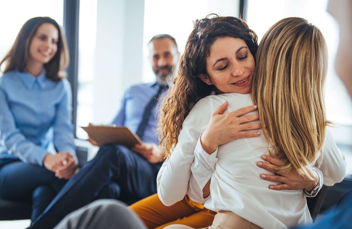 Personas sentadas en círculo en una sala acogedora de terapia en grupo.